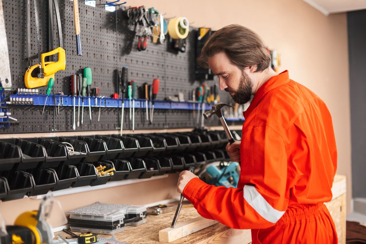 Technician in orange work clothes using tools in a workshop